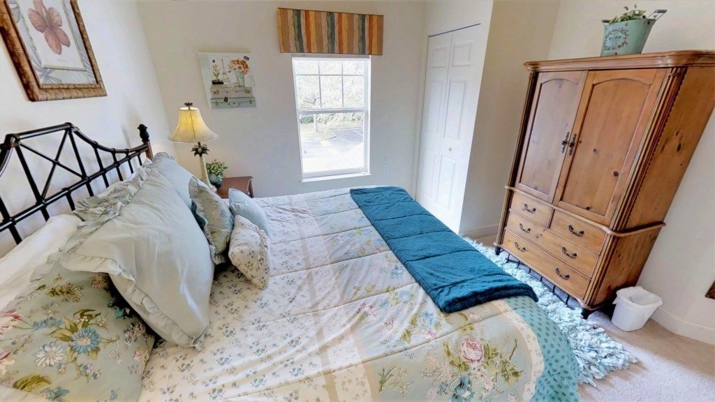 A bedroom with a bed, a dresser, a window, and a lamp.