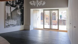 A spacious room with a large industrial-style painting on the wall, a chandelier, and a view through a glass door to an outdoor area. - MAZZONI 15 MODERN FLAT BY VENICE TRAIN STATION (Venezia)
