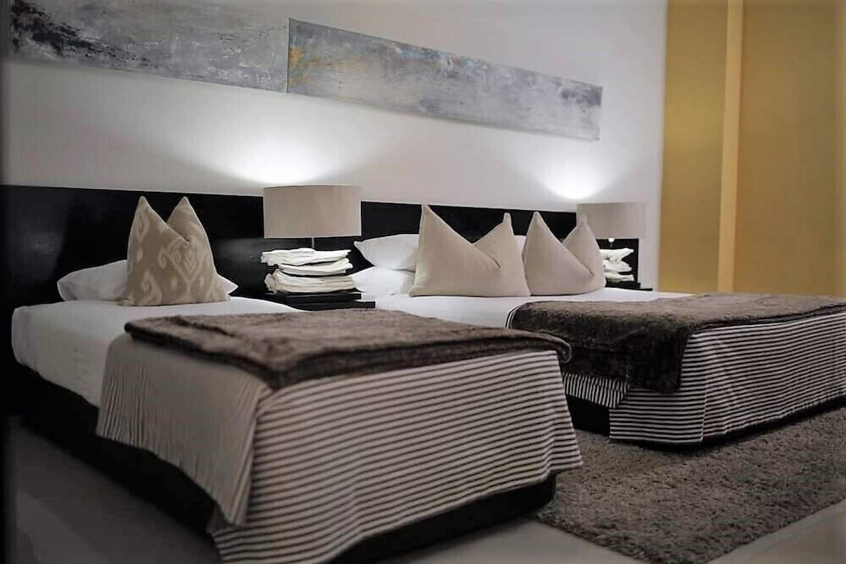 Une chambre d’hôtel moderne avec un grand lit, deux tables de chevet, une lampe et un tableau au mur.