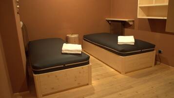Cozy retreat with two beds, a wall-mounted shelf, and a radiator.