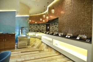 Un espace buffet doté d’un comptoir incurvé, de différents récipients contenant de la nourriture et d’un mur orné de motifs.