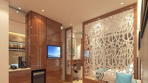 A modern living room with a wooden cabinet, a television, and a decorative partition. - Effotel By Sayaji Vadodara (Vadodara)