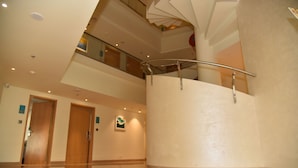 A multi-level interior with a polished floor, a spiral staircase, and a glass railing. - Effotel By Sayaji Vadodara (Vadodara)