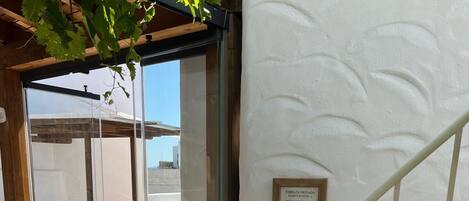 A private room entrance with a glass door, a white textured wall, and a metal staircase.