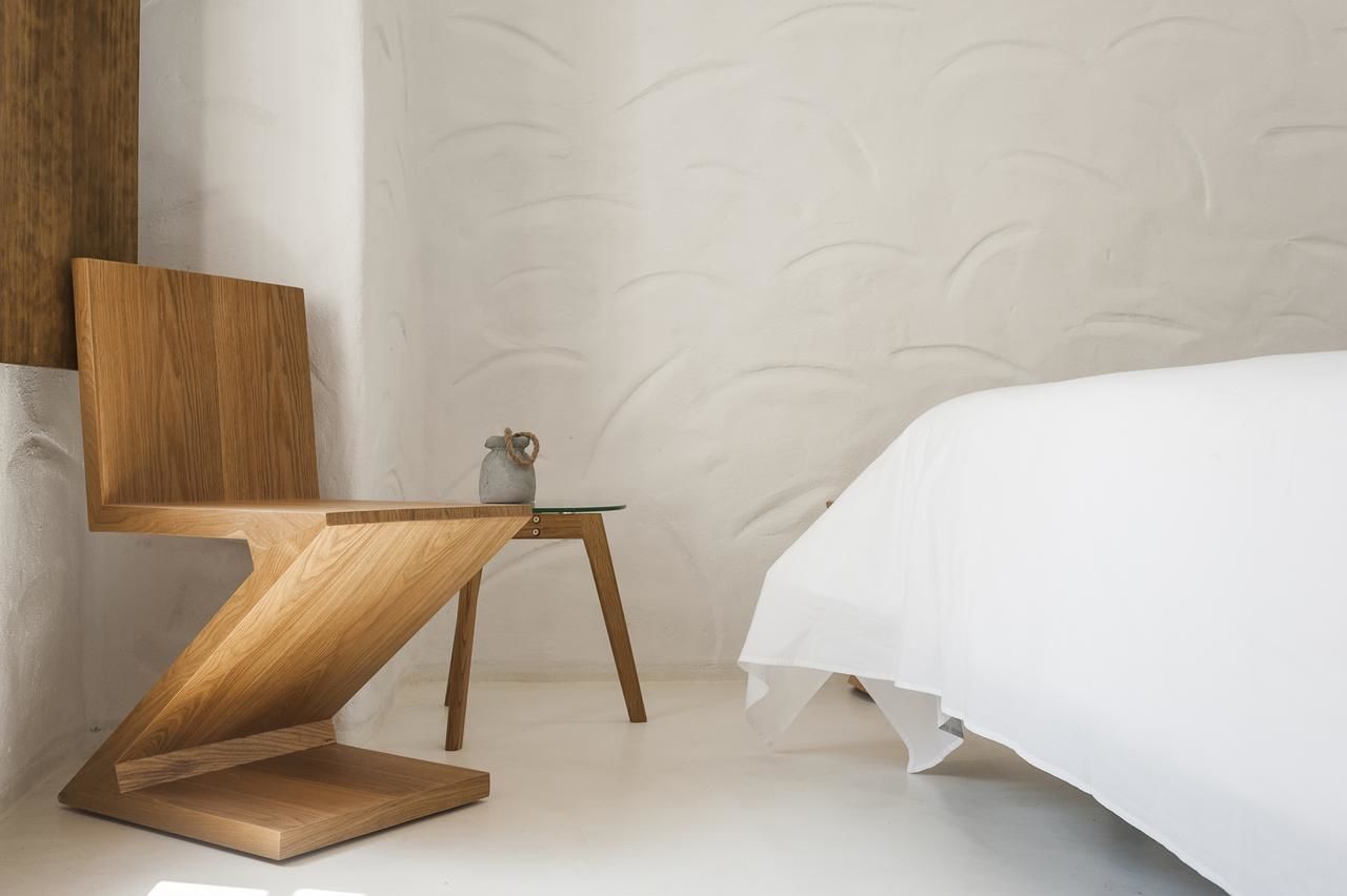 A modern bedroom with a wooden chair, a small table, and a bed.