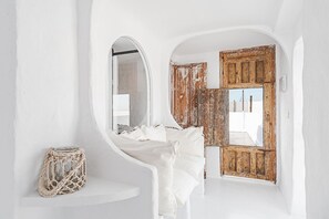 Ein heller Raum mit einem Bett, einer Holztür und einem kleinen Fenster.