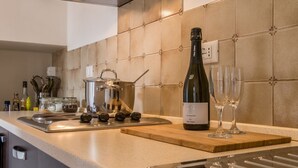 Une cuisine avec une cuisinière, des casseroles, une bouteille de vin et des verres sur le comptoir.