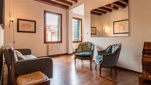 Une pièce spacieuse avec un plancher en bois, un canapé, deux fauteuils et un meuble en bois.