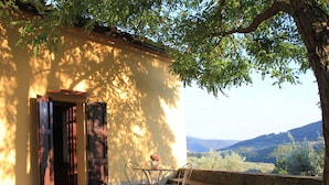 Un espace extérieur aménagé avec une table et des chaises, un banc et une vue sur le paysage.