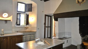 Une cuisine avec des meubles en bois, un plan de travail en marbre et un luminaire suspendu.