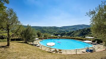 Una piscina al aire libre de temporada, sombrillas