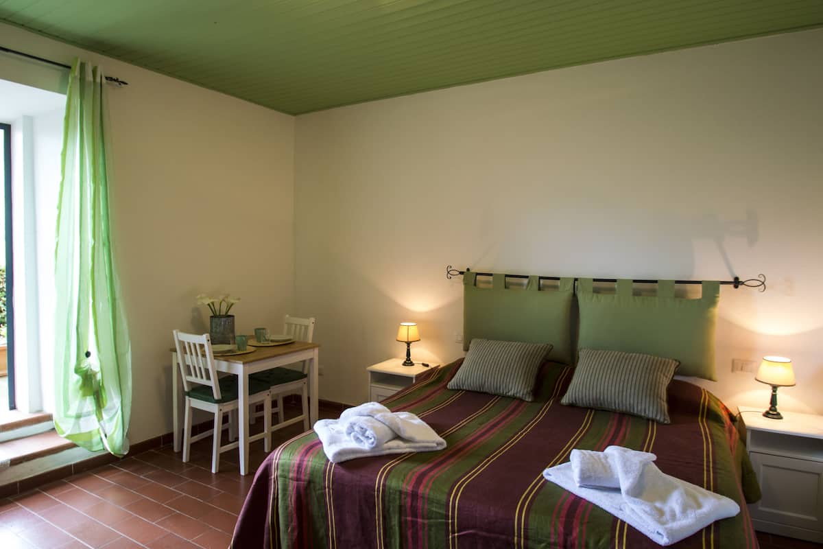 Een hotelkamer met een bed, een bureau, een stoel, twee bedlampjes en een raam met gordijnen.