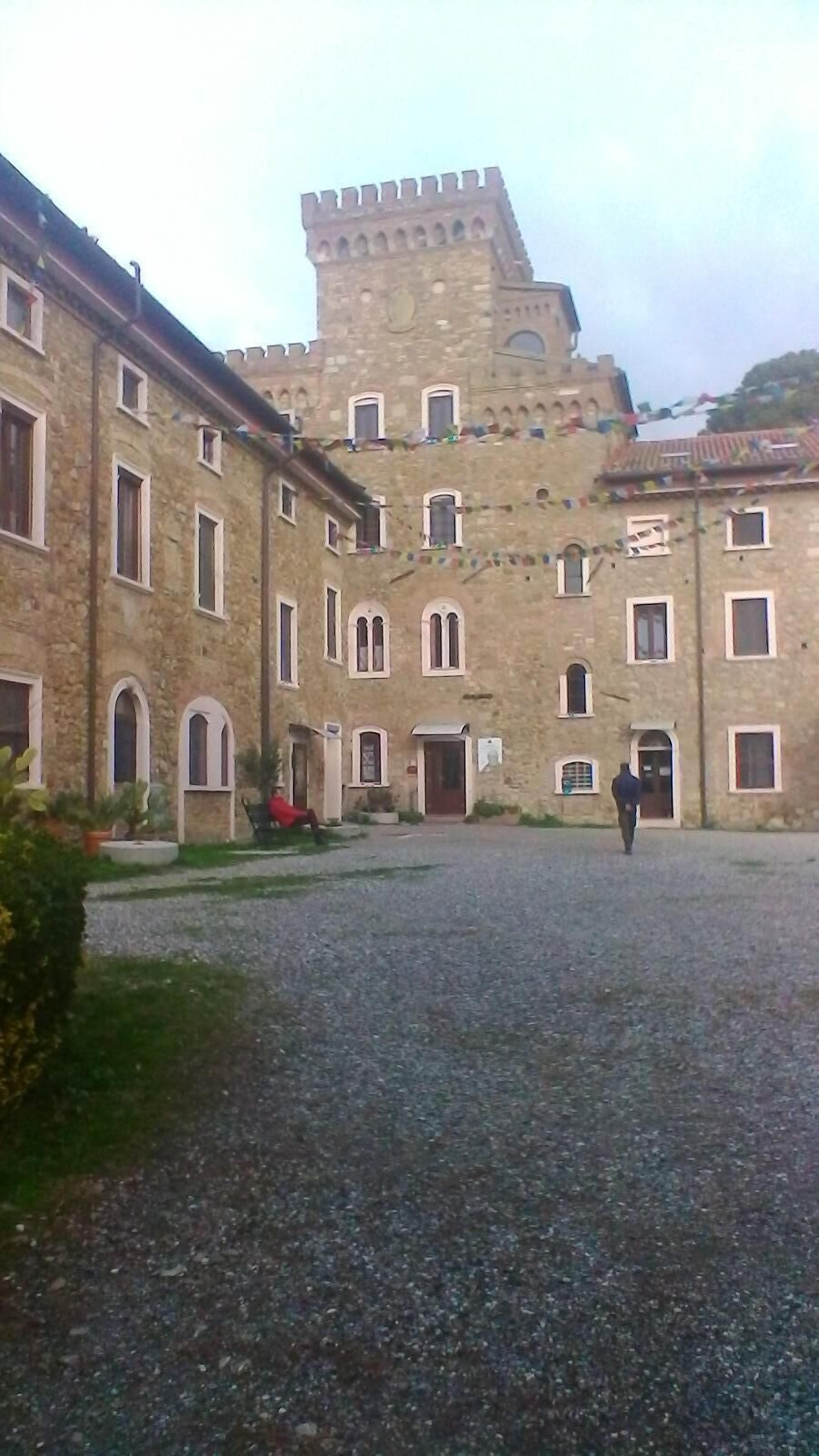 A courtyard with a historic building featuring arched windows and a central tower.