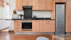 A modern kitchen with wooden cabinets, stainless steel appliances, and a glass dining table. - 66 Keerom 715 (Cape Town)