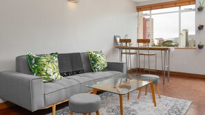 A modern living room with a grey sofa, glass coffee table, and a dining area with a wooden table and chairs. - 66 Keerom 715 (Cape Town)
