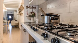 Una cocina moderna con estufa a gas, electrodomésticos de acero inoxidable y tabla de cortar de madera.