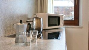A kitchen with a coffee maker, a microwave, and three glasses on the counter. - Appartamenti Brunnlein (Livigno)