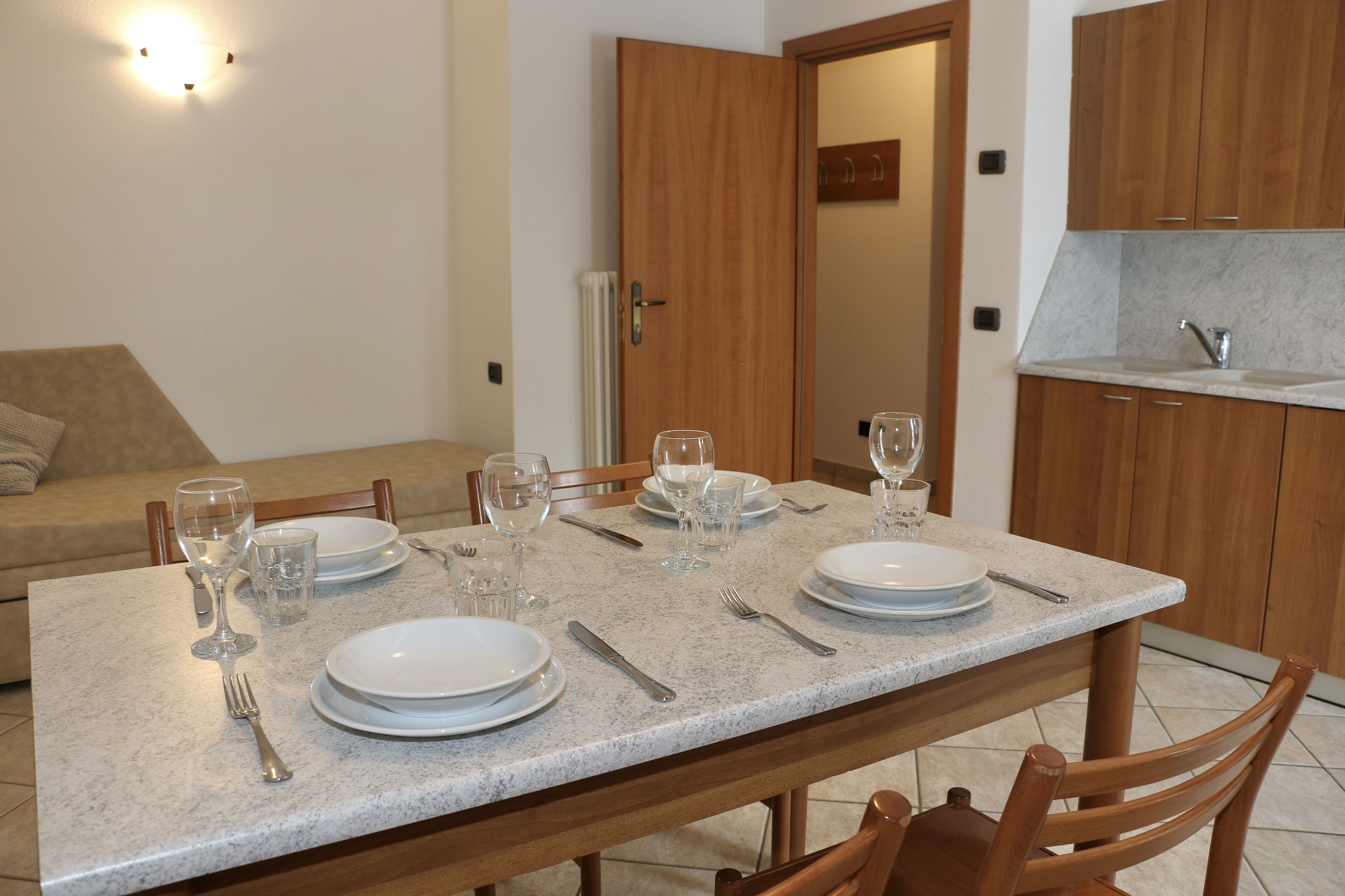 A dining area with a table set for four, including plates, cutlery, and glasses.