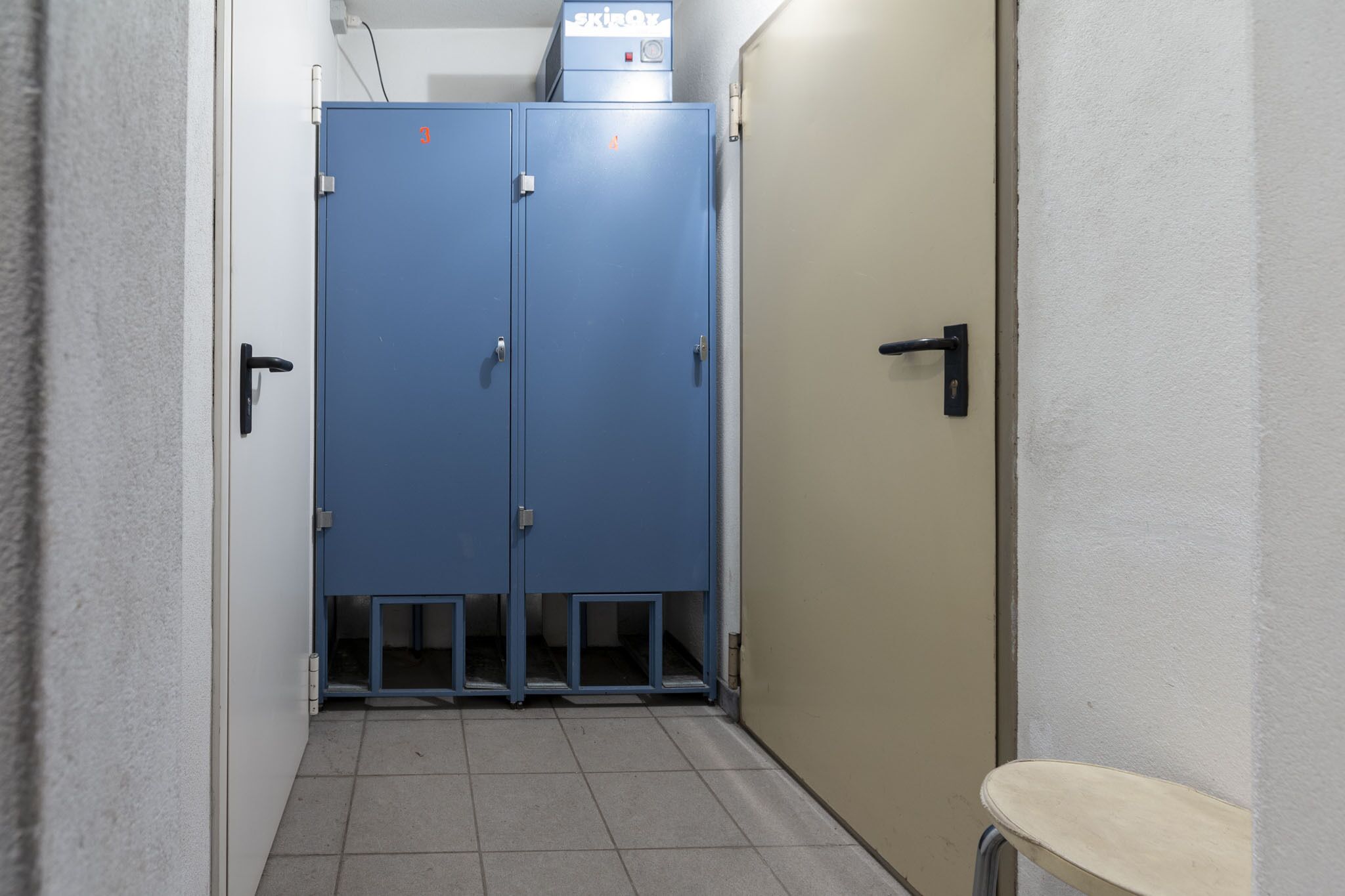 A narrow hallway with a blue locker and a beige door.