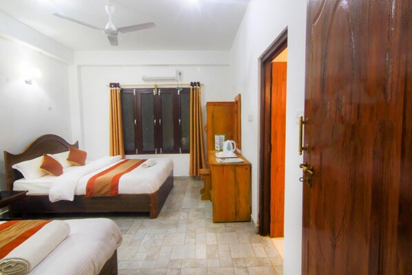 Una habitación de hotel con dos camas, un escritorio, un armario y una puerta.