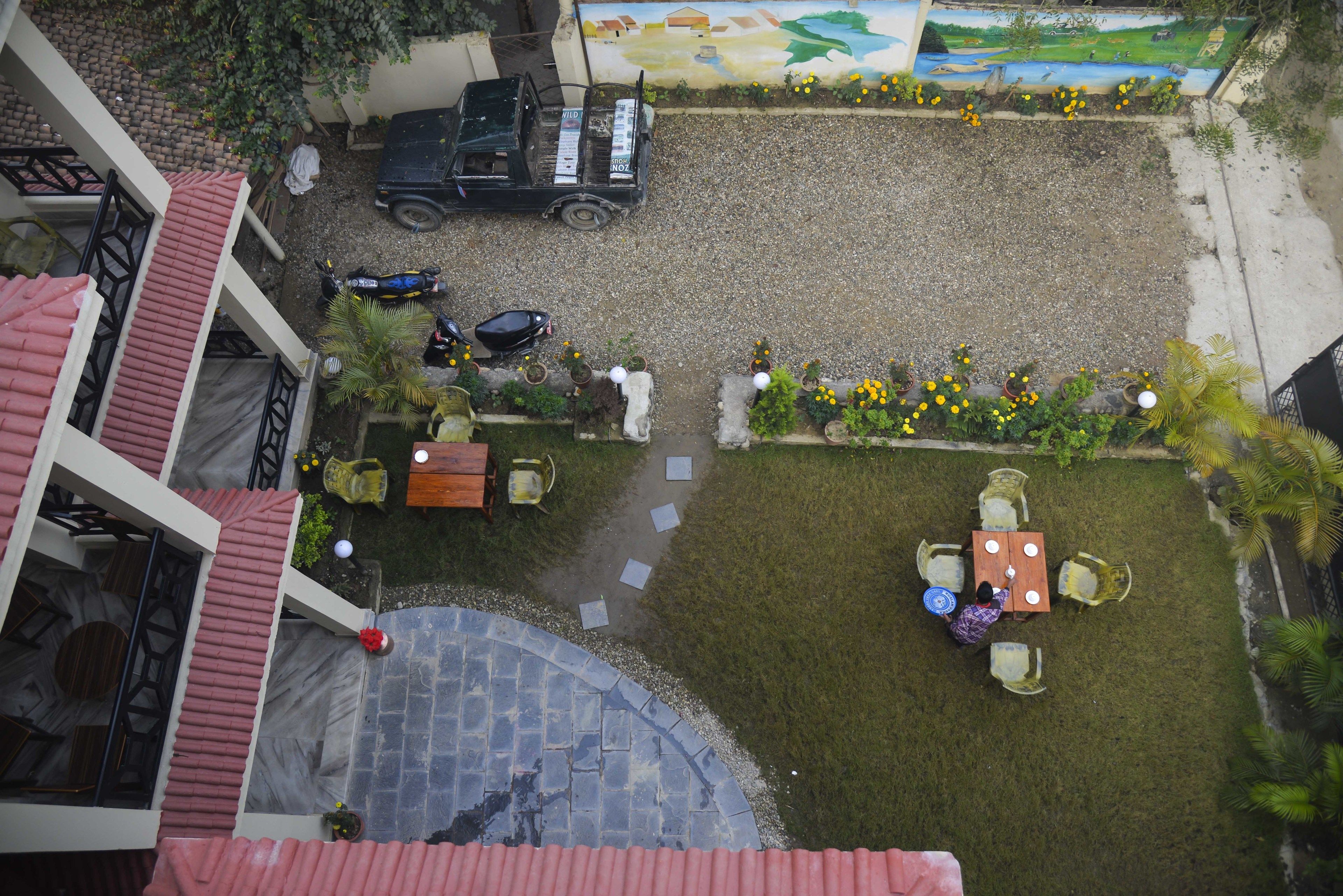 Un patio con camino de grava, una mesa y sillas, y un mural en la pared.