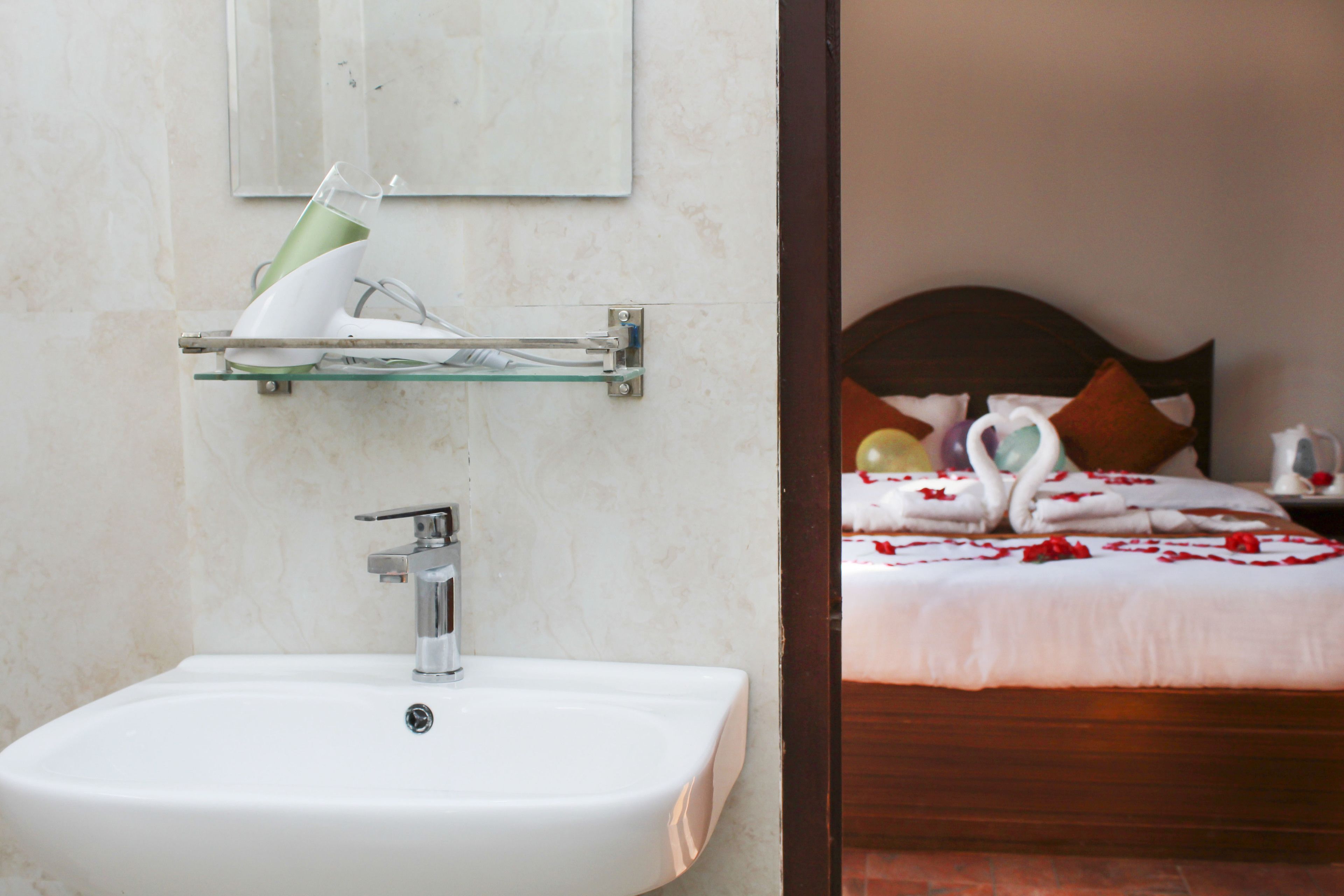 A bathroom with a white sink, a glass shelf above it, and a mirror on the wall.