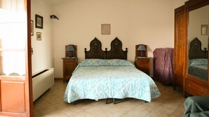 Un dormitorio con cama, dos mesitas de noche, un armario y un radiador.
