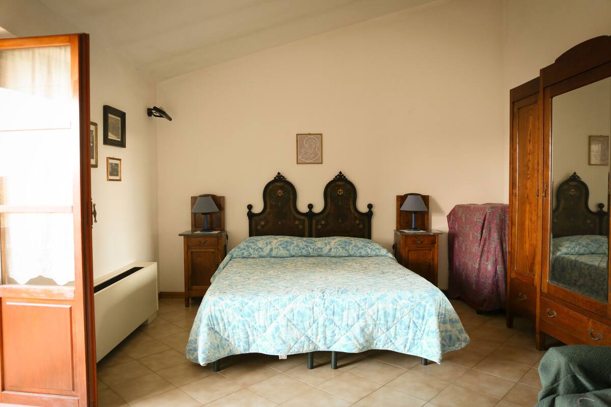 Un dormitorio con cama, dos mesitas de noche, un armario y un radiador.