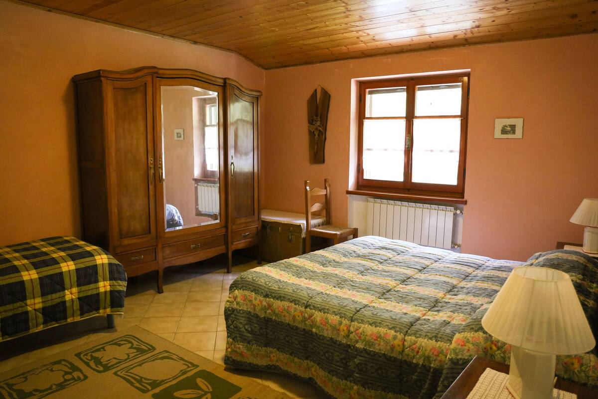 Un dormitorio con un armario de madera, una cama con cubierta floral, una ventana con persianas y un radiador.