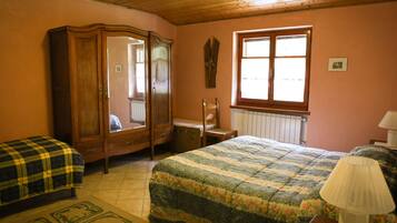 Un dormitorio con un armario de madera, una cama con cubierta floral, una ventana con persianas y un radiador.