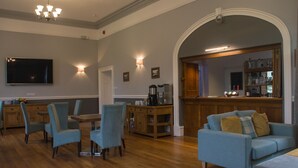 Un salón espacioso con suelo de madera, un sofá azul y una zona de comedor con sillas azules.
