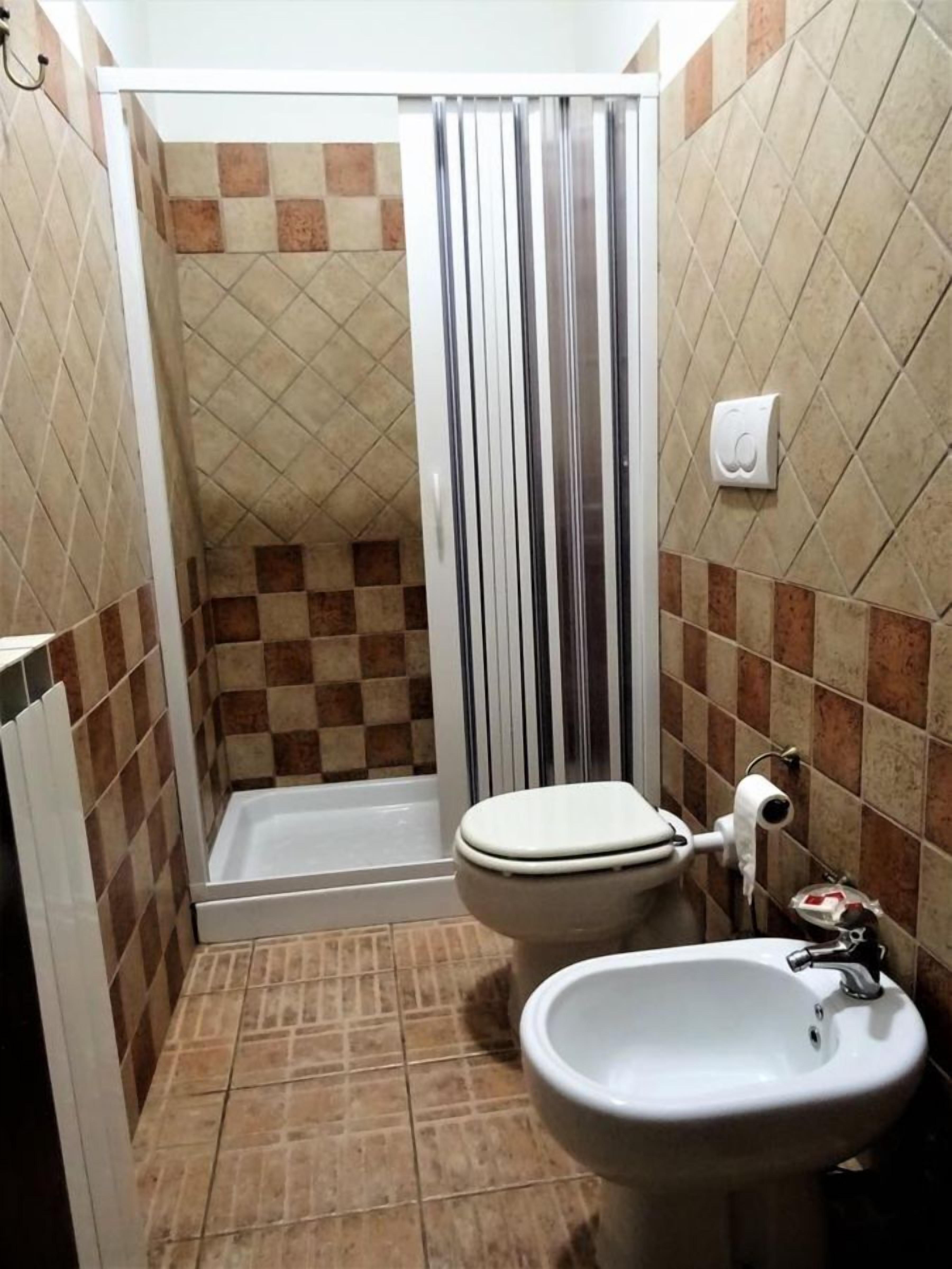 Une petite salle de bain avec douche, toilettes et lavabo.
