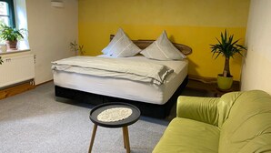 A bedroom with a bed, a green chair, a small round table, and potted plants. - Grüne Idylle im Dresdener Süden (Bannewitz)