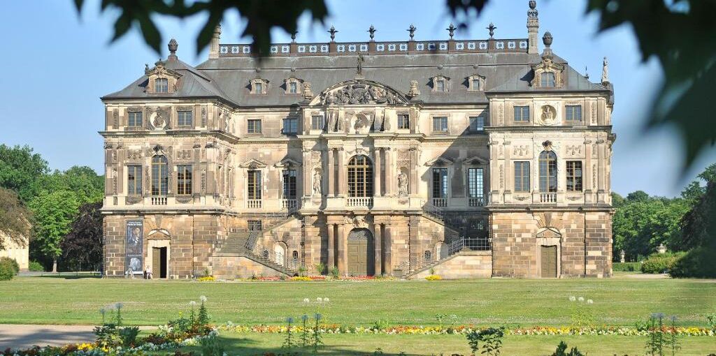 Un grand bâtiment historique à la façade symétrique, doté de nombreuses fenêtres et d’une entrée centrale.