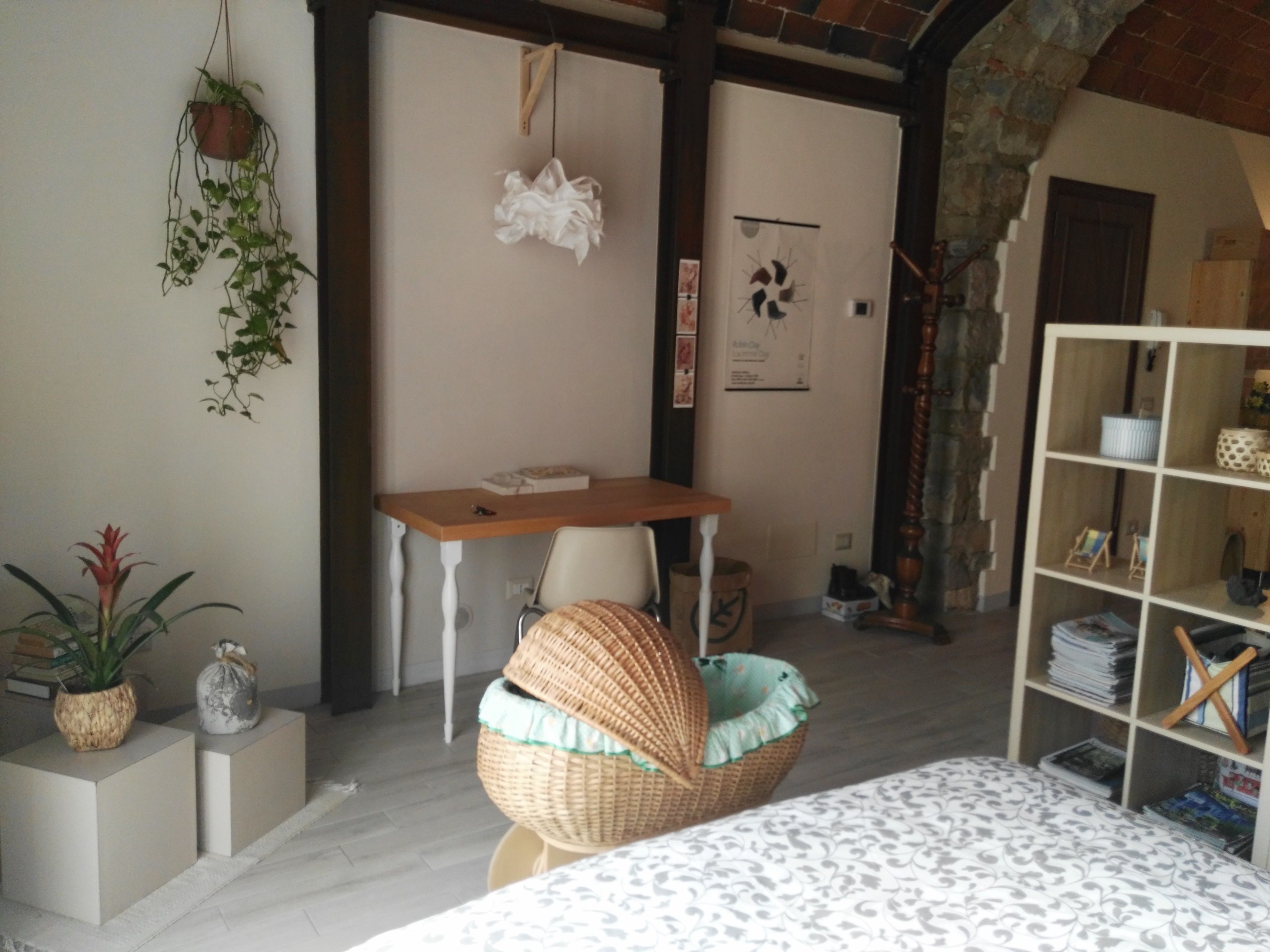 A cozy room with a bed, a wicker chair, a desk, and a bookshelf.