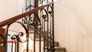 Eine Treppe mit aufwendiger Metallreling und hölzernem Geländer.
