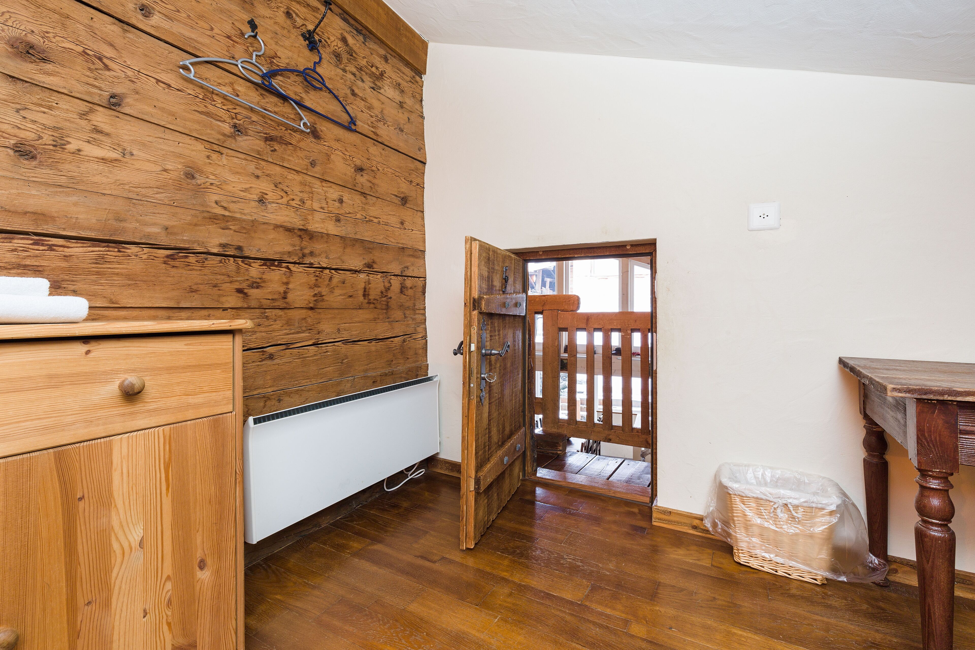Una habitación con paneles de madera, un radiador blanco, una puerta de madera y un objeto envuelto en plástico en el suelo.