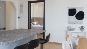 Une cuisine moderne avec un plan de travail en marbre, des chaises noires et une table à manger en bois.