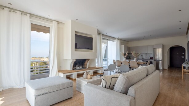 Un salon moderne avec un canapé, un pouf et un téléviseur fixé au mur.
