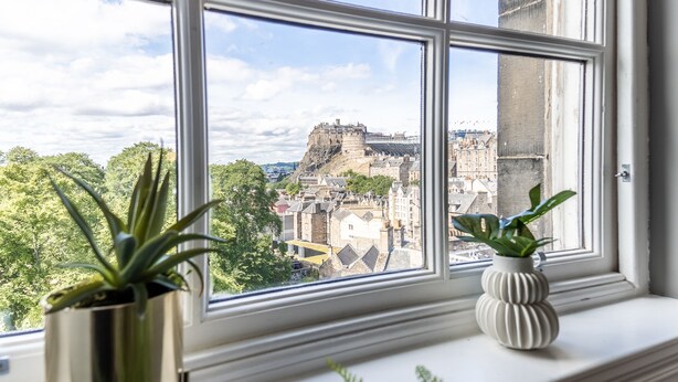 A window with two potted plants and a view of a historic castle. - No1. Apartments Edinburgh - George IV Bridge (Edinburgh)