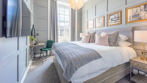 A hotel room with a large bed, a desk with a chair, a TV, and artwork on the wall. - No1. Apartments Edinburgh - George IV Bridge (Edinburgh)