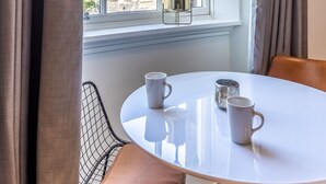 A room with a large window, a round table with two mugs, a chair, and a potted plant. - No1. Apartments Edinburgh - George IV Bridge (Edinburgh)