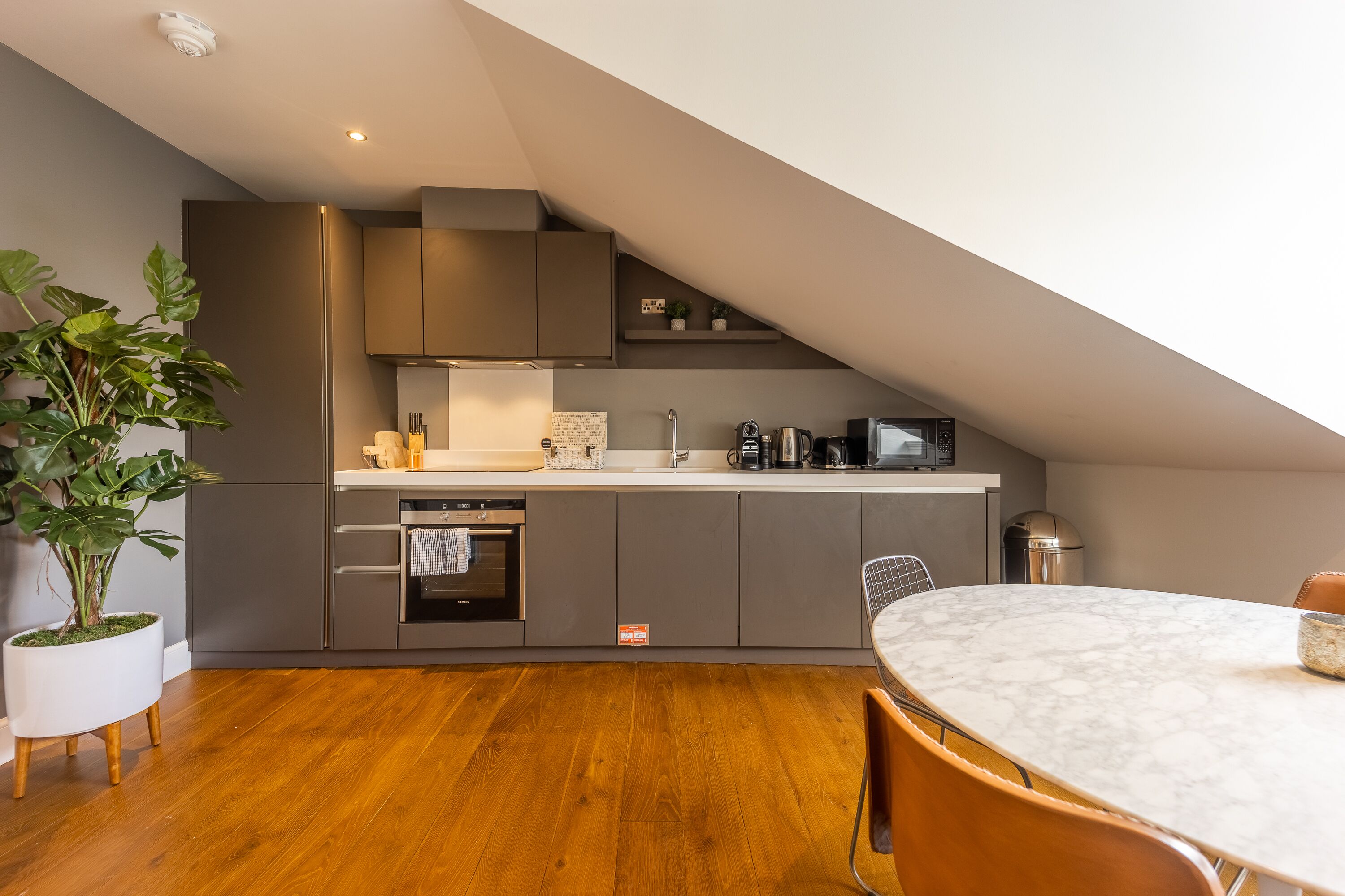 A modern kitchen with grey cabinets, a white countertop, and a built-in oven.