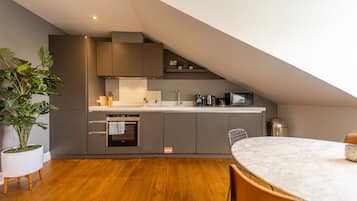 A modern kitchen with grey cabinets, a white countertop, and a built-in oven.