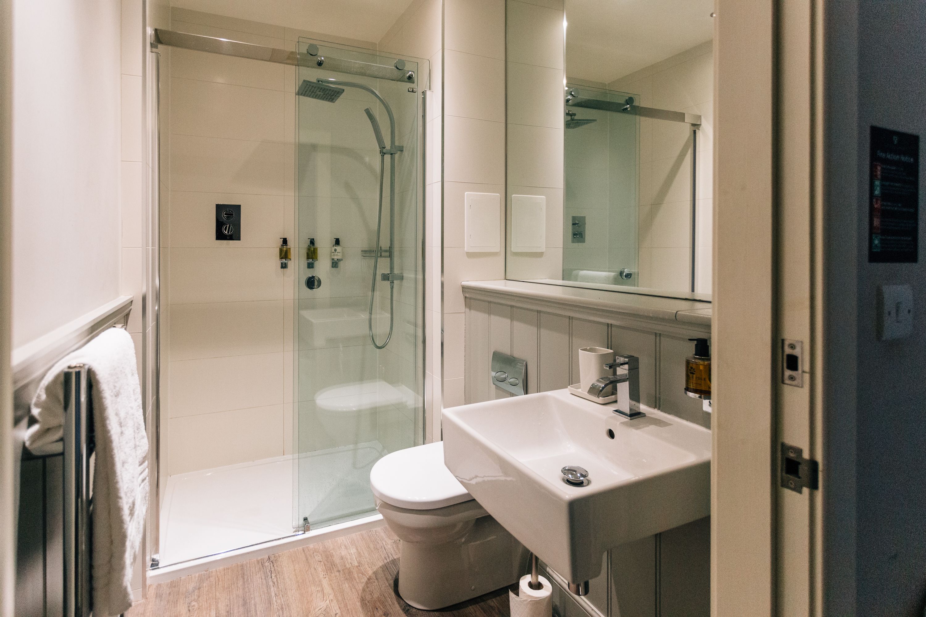 Un baño moderno con ducha de vidrio, un lavamanos blanco y un inodoro.