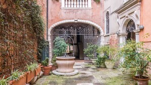 Un cortile con una fontana al centro, piante in vaso e un muro in mattoni.