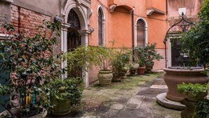 Un cortile con pavimento in pietra, piante in vaso e un muro in mattoni.