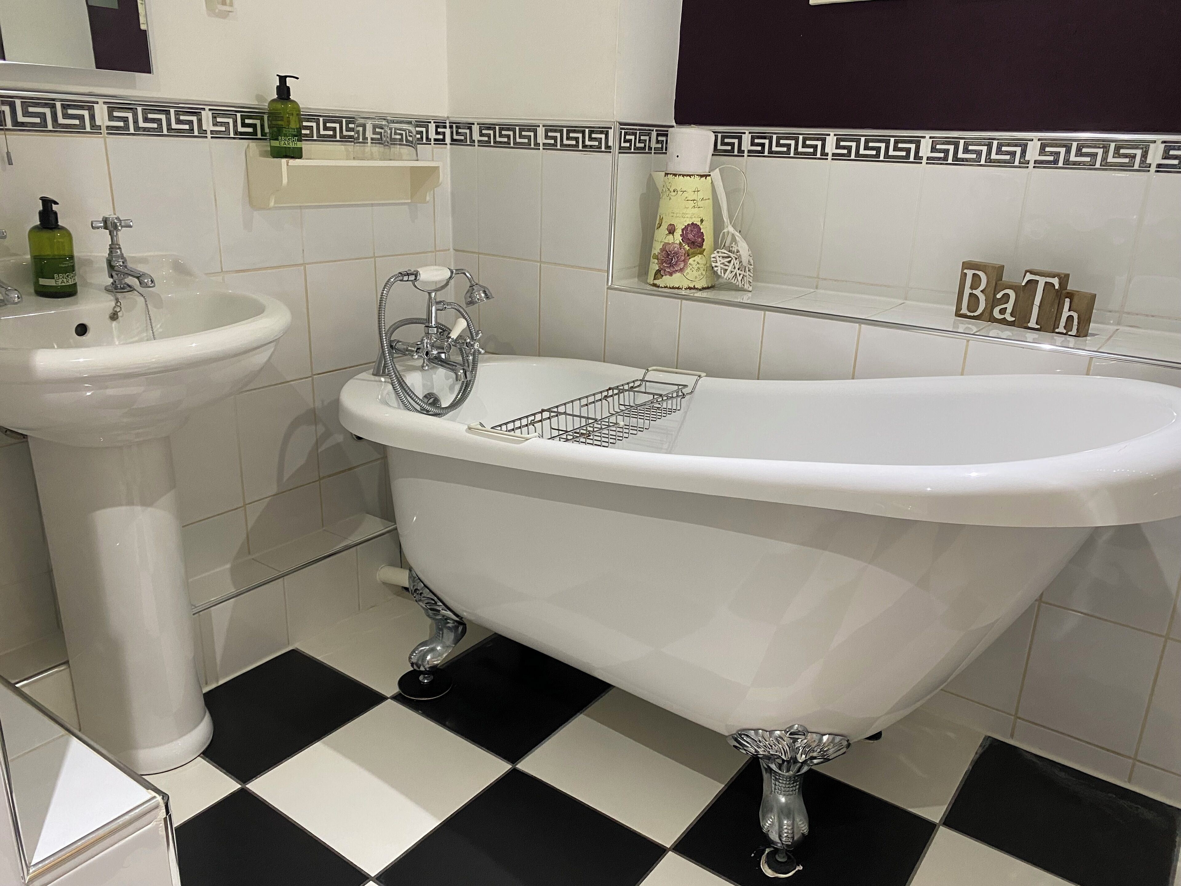 Un baño con una bañera independiente, un lavamanos sobre pedestal y un tocador con espejo.