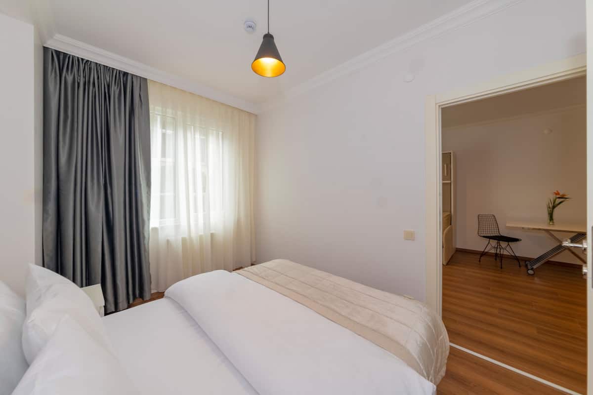 A hotel room with a bed, a desk, and a chair.
