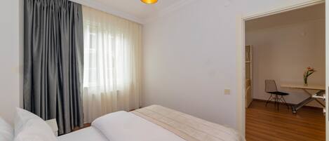A hotel room with a bed, a desk, and a chair.
